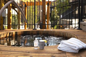 Eine Holzterrasse mit Whirlpool, einer Wasserflasche, einem Glas und einem Handtuch.