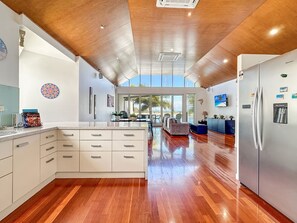 A spacious kitchen with a large island, wooden flooring, and a view to the outside. - Solmar At The Waters Edge (Nelly Bay)