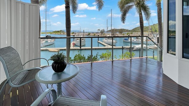 Uma varanda com vista para uma marina, uma mesa com uma planta e uma cadeira.