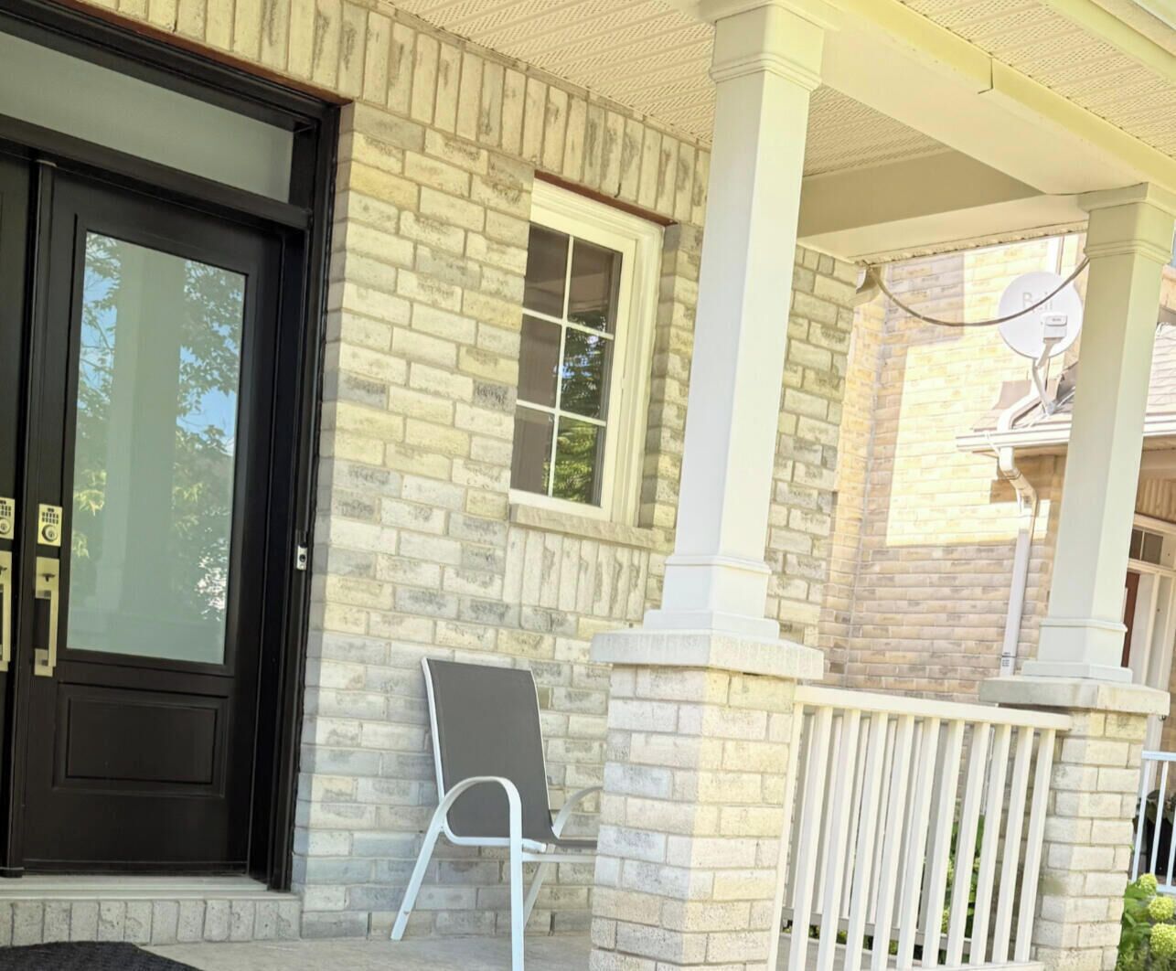 A house with a black front door, a window, and a porch with a white railing.