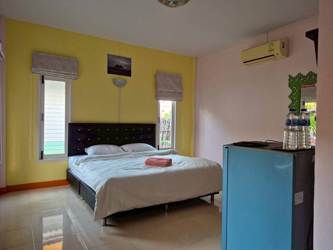 Un dormitorio con cama, un refrigerador azul y ventana con vistas.