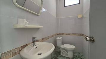 Une petite salle de bain avec un lavabo blanc, des toilettes et un miroir au-dessus du lavabo.