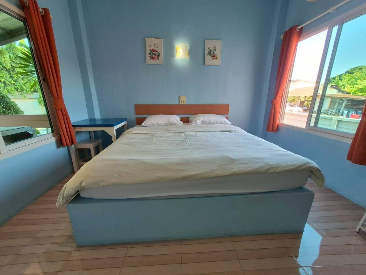 A bedroom with a bed, a nightstand, a window with curtains, and two wall-mounted light fixtures.