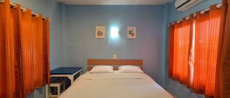 Un dormitorio con cama, dos almohadas, una mesita de noche, un equipo de aire acondicionado y dos cuadros en la pared.