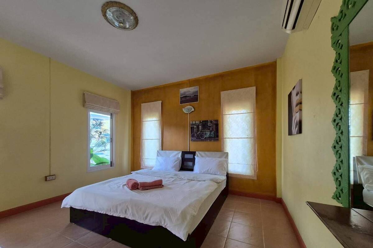 Ein Schlafzimmer mit Bett, Fenster und einer Wand-Klimaanlage.