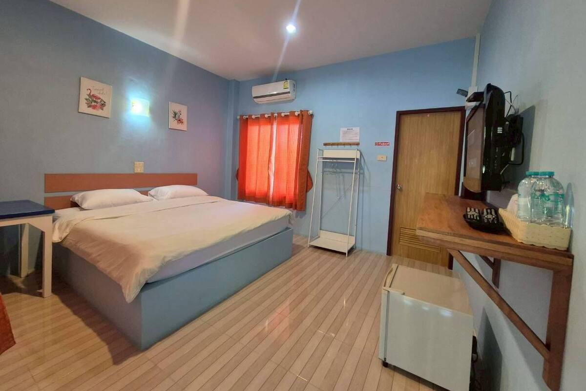 Ein Hotelzimmer mit Bett, Schreibtisch, Fernseher, Klimaanlage und einem Fenster mit Vorhängen.