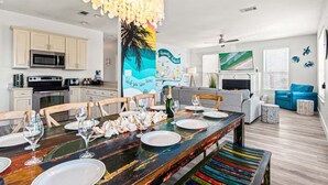 A modern kitchen with white cabinets, a microwave, and a dining area with a colorful table.
