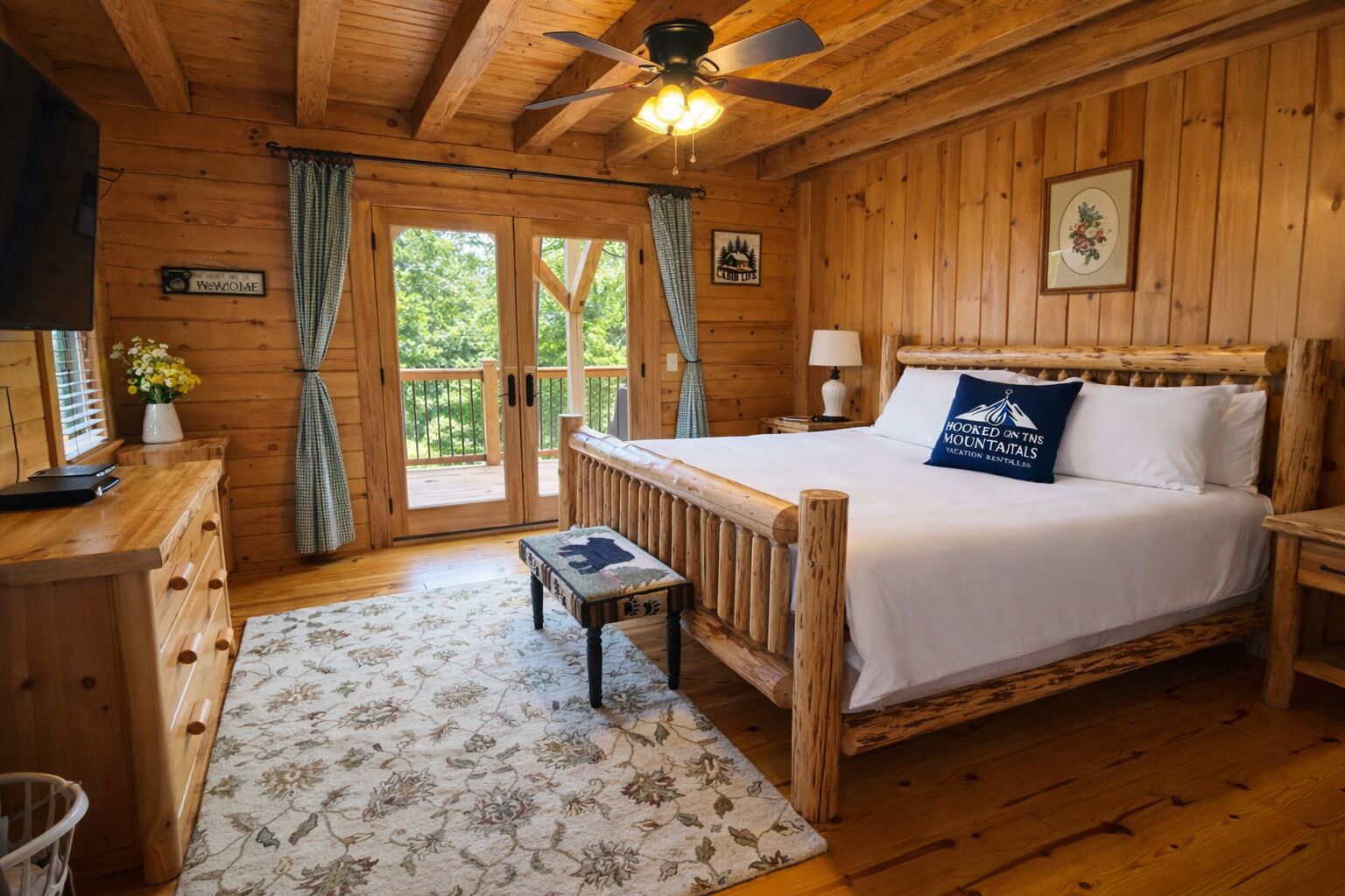 Un dormitorio de cabaña de madera con cama, escritorio, silla, una mesita y un ventilador de techo.