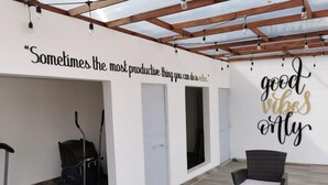 Ein überdachter Außenbereich mit Decke und Wänden, der ein Zitat und ein Schild mit der Aufschrift 'good vibes only' zeigt.
