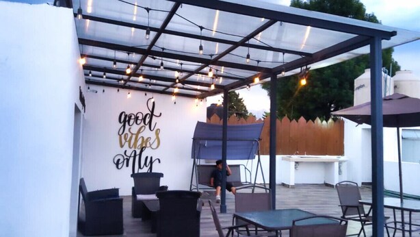 Eine Terrass mit Pergola, Sitzgelegenheiten und einer Wand mit motivierenden Texten.