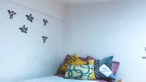 Ein Bett mit Holzrahmen, ein Schreibtisch mit einem Laptop und eine Wand mit Dekorationen.
