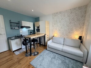 A compact living space with a kitchenette, a dining area, and a sofa. - Petit Studio au coeur de Biarritz (BIARRITZ)