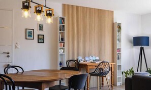 Ein Essbereich mit Holztisch, Stühlen, einem Bücherregal und einer Stehlampe.