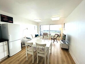 Eine moderne Küche mit Essbereich, weißen Geräten und Blick durch große Fenster.