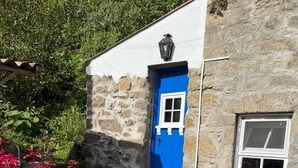 Un edificio de piedra con una puerta azul y un ventanal pequeño.