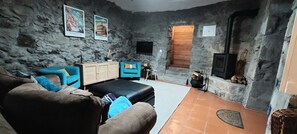 Une pièce rustique aux murs de pierre, avec un canapé, un banc en bois, une armoire et une cheminée.