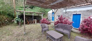 Un espace extérieur aménagé dans un style rustique, avec une pergola, un mur en pierre et une porte bleue.