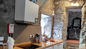 Una cocina compacta con un arco de piedra, horno empotrado y lavamanos.