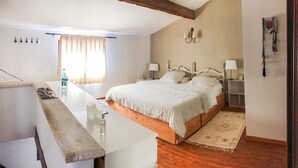 A bedroom with a wooden bed, bedside tables, a nightstand, a window with curtains, and a wall-mounted light fixture. - Gîte dans Mas proche Alpilles (Saint-Martin-de-Crau)