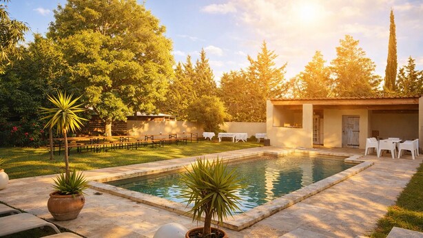 A pool area with a patio, seating, and potted plants. - Gîte dans Mas proche Alpilles (Saint-Martin-de-Crau)
