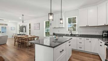 A modern kitchen with white cabinets, granite countertops, and a dining area with wooden chairs.