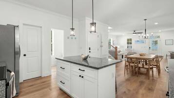 A modern kitchen with white cabinetry, a granite countertop, and pendant lighting.