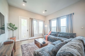 A living room with a sofa, a coffee table, a plant, and a sliding door leading to a balcony. - 3-bedroom house in nice Houston with cool AC for relaxing stay (Houston)