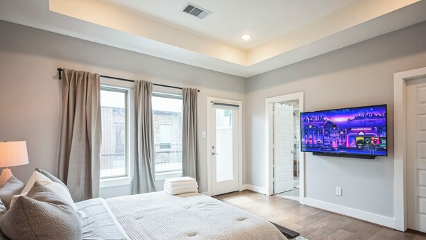 A bedroom with a bed, curtains, a television, and a city view. - 3-bedroom house in nice Houston with cool AC for relaxing stay (Houston)