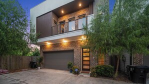 A two-story house with a garage, a balcony, and a well-lit entrance. - 3-bedroom house in nice Houston with cool AC for relaxing stay (Houston)