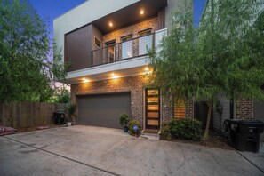 Ein zweistöckiges Haus mit Garage, Balkon und einer gut beleuchteten Eingangsparte.