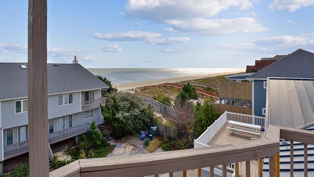 A coastal residential area with a view of the beach, wooden deck, and a two-story house. - Walk to Beach | 4BR Beach House w/ Decks + Kitchen (Tower Shores)
