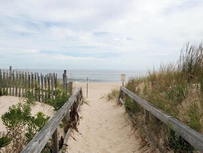 A sandy beach path with wooden railings and a signpost. - Walk to Beach | 4BR Beach House w/ Decks + Kitchen (Tower Shores)