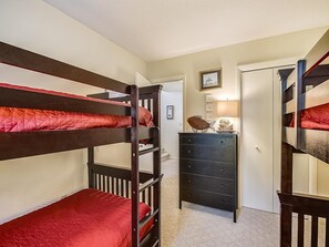 A bunk bed room with a dresser and a lamp. - Walk to Beach | 4BR Beach House w/ Decks + Kitchen (Tower Shores)