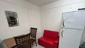 A compact kitchen with a wooden dining table, a single wooden chair, a red sofa, and a white refrigerator. - Apartment Amanecer Isleño 7 5 min from the beach (Isla Mujeres)