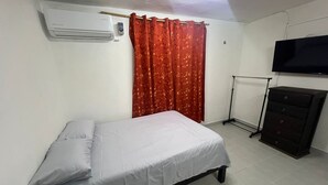 A bedroom with a bed, a dresser, a TV, and an air conditioner. - Apartment Amanecer Isleño 7 5 min from the beach (Isla Mujeres)