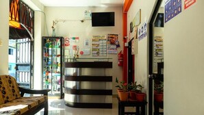 Un área de recepción con mostrador, plantas en macetas y carteles informativos en la pared.