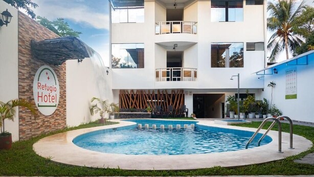 Un hotel con piscina, un cartel que dice 'Refugio Hotel' y una fachada de edificio moderna.