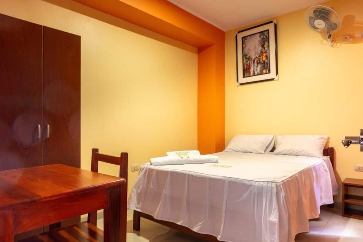 A bedroom with a bed, a wooden table, and a wardrobe.
