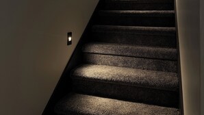 Una scala con gradini rivestiti di moquette e luci a parete.