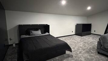 Un dormitorio con cama, una silla y un escritorio pequeño.