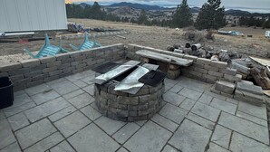 Una zona patio con un braciere in pietra, posti a sedere all'aperto e vista su un paesaggio collinare.