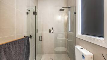 Een moderne badkamer met een douchecabine van glas, een toilet en een bidet.