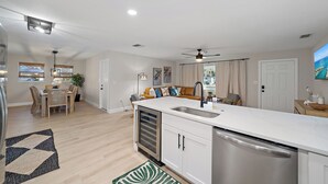 Een moderne keuken met een inbouwvaatwasser, een eethoek met een tafel en stoelen, en een zithoek met een bank en een televisie.