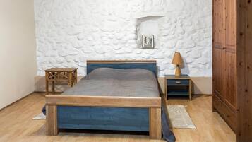 Una camera da letto con un letto in legno, un comodino con una lampada, un piccolo tavolo e un armadio.