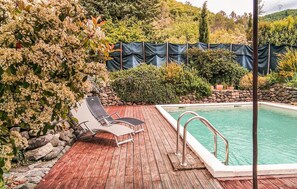 A wooden deck with a pool, surrounded by greenery and a stone wall. - Gîte piscine privée dans Mas (Saint-Germain)