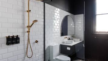 A modern bathroom with white subway tiles, a black shower enclosure, a glass shower door, a white toilet, a vanity with a mirror, and a window.