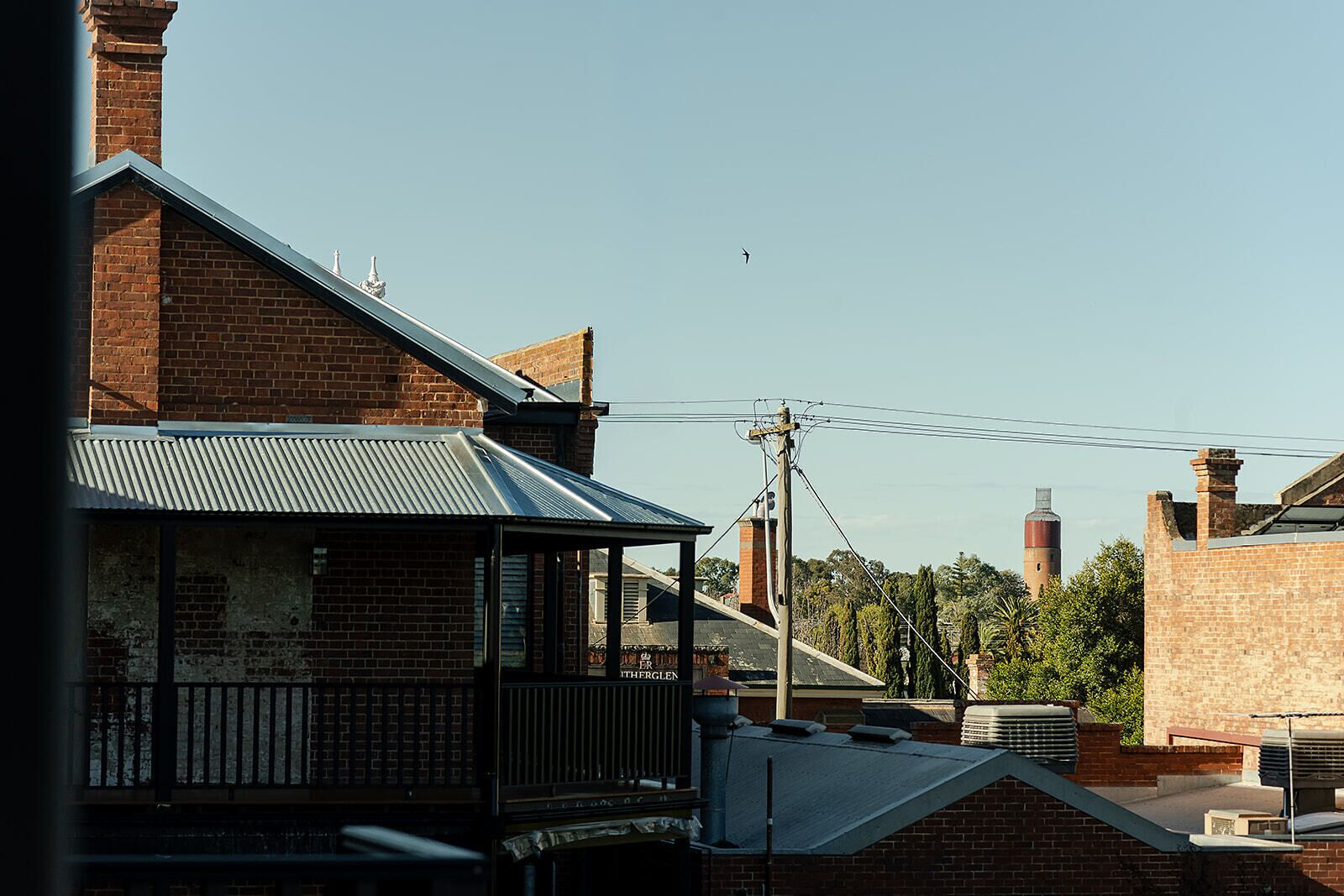 A building with a balcony, brick walls, and a metal roof.