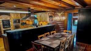 Een landelijke keuken met houten kastjes, een centraal eiland met zitplaatsen en een kroonluchter.