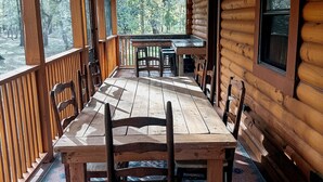 Een houten chalet met een grote eettafel, stoelen en een plafondventilator.