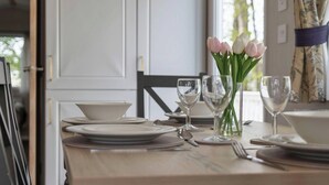 Une table à manger dressée avec des assiettes, des verres et un vase de fleurs.